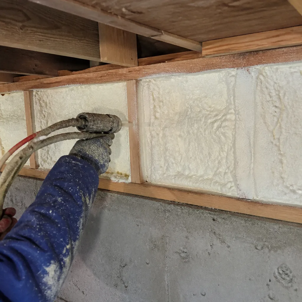 Professional applying spray foam insulation between wall studs